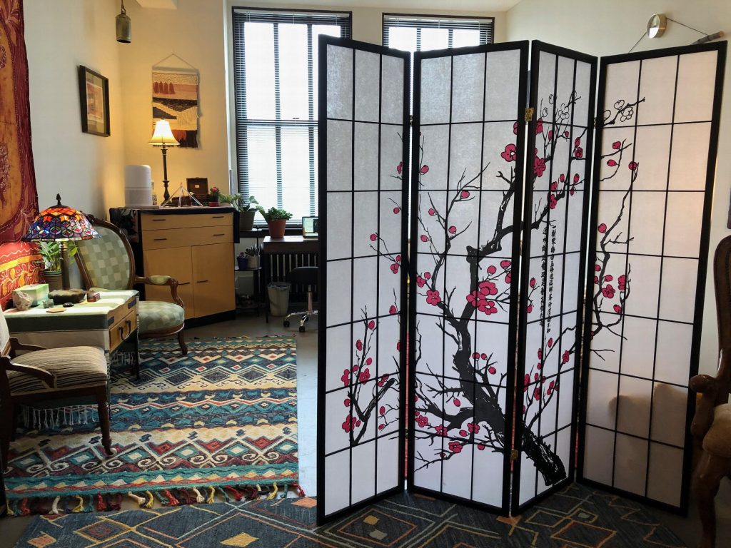 A cherry-blossom folding screen dividing the room, with a desk and armchair by the windows