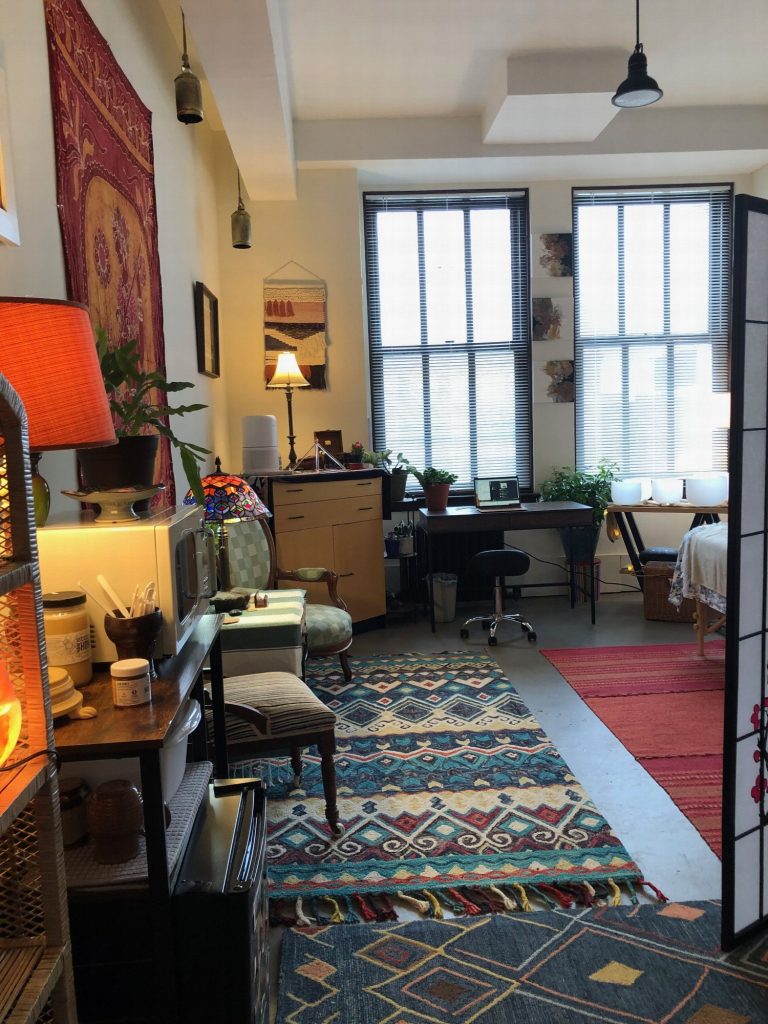 The full length of the office, from the desk area to the tall windows, over layered patterned rugs