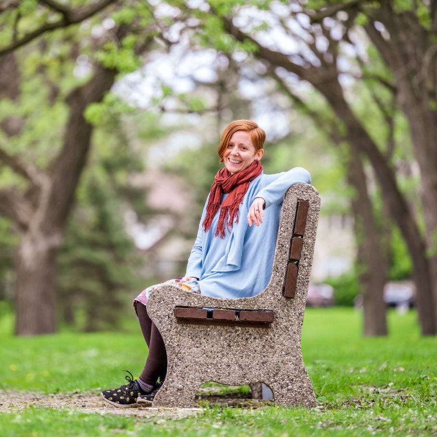 Sally Yunis smiling on a park bench under spring trees